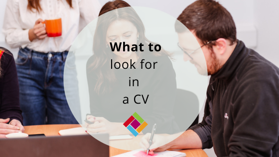 People looking at a CV on a desk